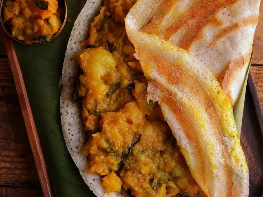 Masala dosa with potato filling and chutneys on a banana leaf