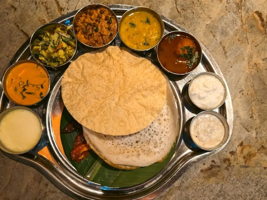 A thali with dosa, papad and small bowls of curry